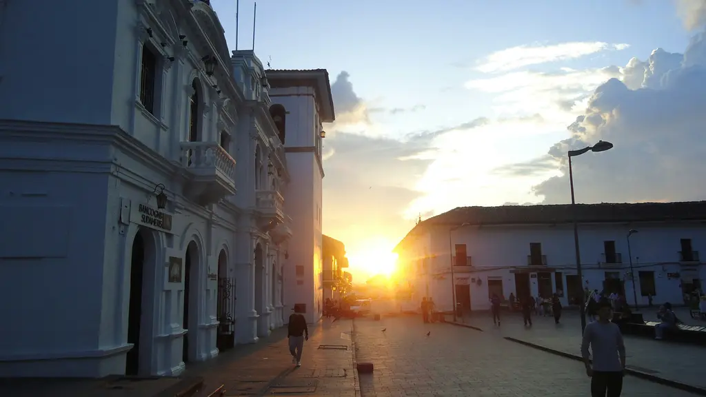 Popayán'da sokak; baştan sona beyaza boyanmış sömürge cepheleri, kemerli geçitler ve taş döşeli yol.