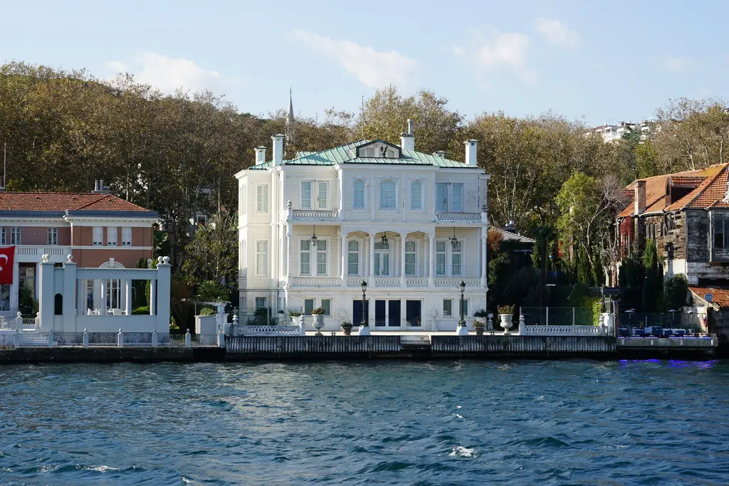 Mısırlı Fuat Bey Yalısı; iki katlı beyaz cephe, kiremit çatı, iki yanında yalılar ve arkada ağaçlar.