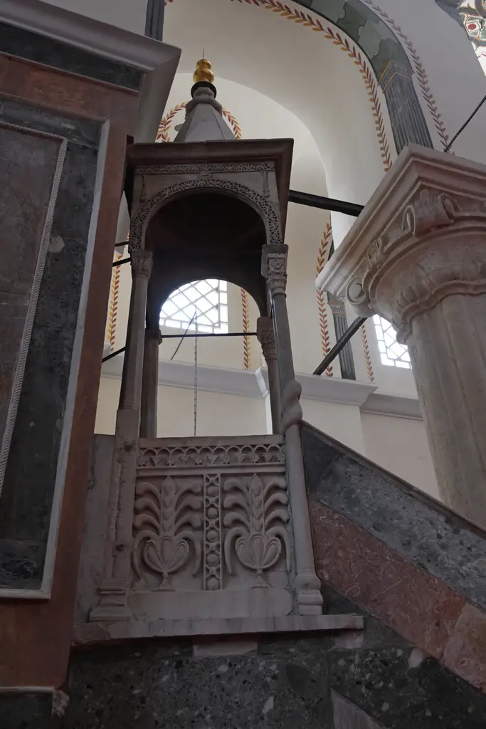 Zeyrek Camii'nin minberi; mermer merdiven, oymalı korkuluk, dört ince sütuna oturan külahlı köşk ve tepesinde altın rengi alem.