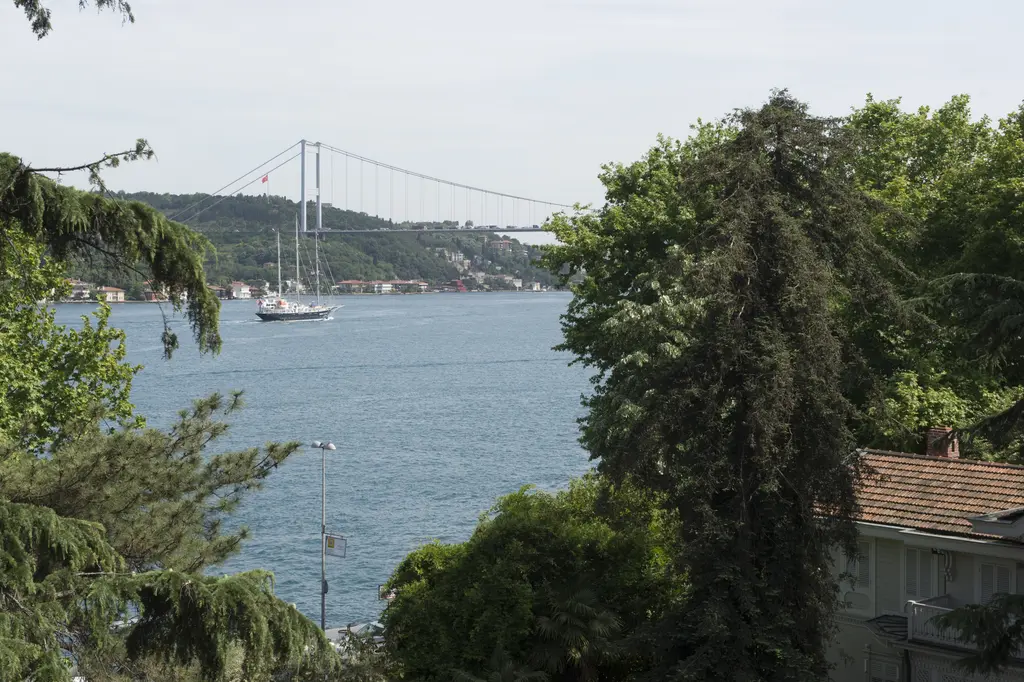 Sakıp Sabancı Müzesi bahçesinden Boğaz; ağaçların arasından mavi deniz, geçen gemiler ve uzakta asma köprü.