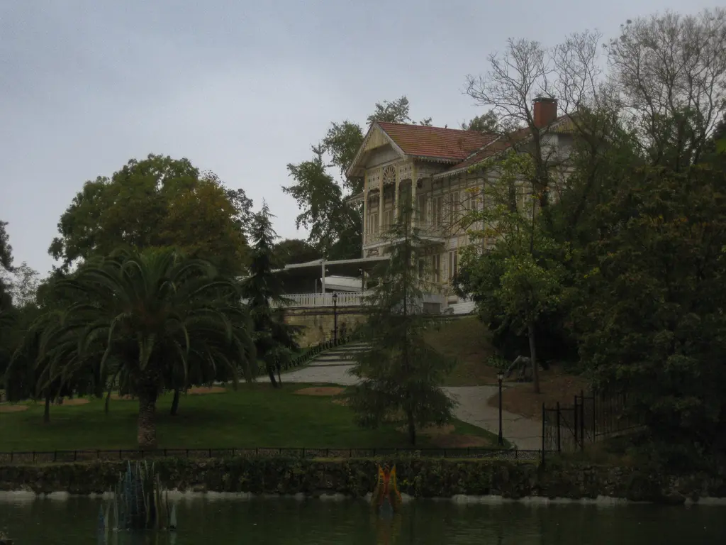 Emirgan Korusu'nda Sarı Köşk; ağaçlık tepede sarı ahşap köşk, önünde çimenlik ve gölet, bulutlu akşam.