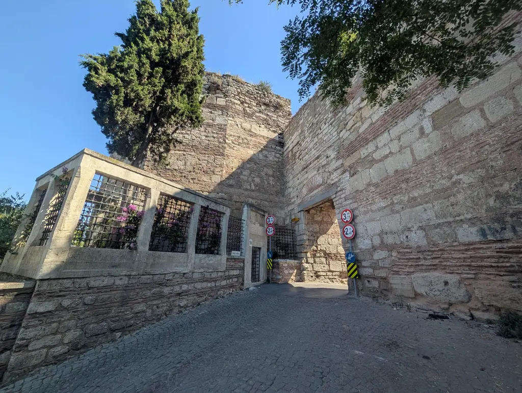 Eğrikapı; surun içinden geçen dar kemerli geçit, önünde yükseklik sınırı levhaları, arkada yıkık bir kule ve arnavut kaldırımı.