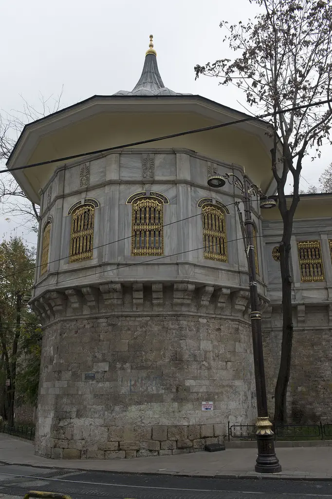 Alay Köşkü'nün burcu; kesme taştan yuvarlak kaide, üstünde mermer salon, altın sarısı pencereler, soğan kubbe ve yanında sokak lambası.
