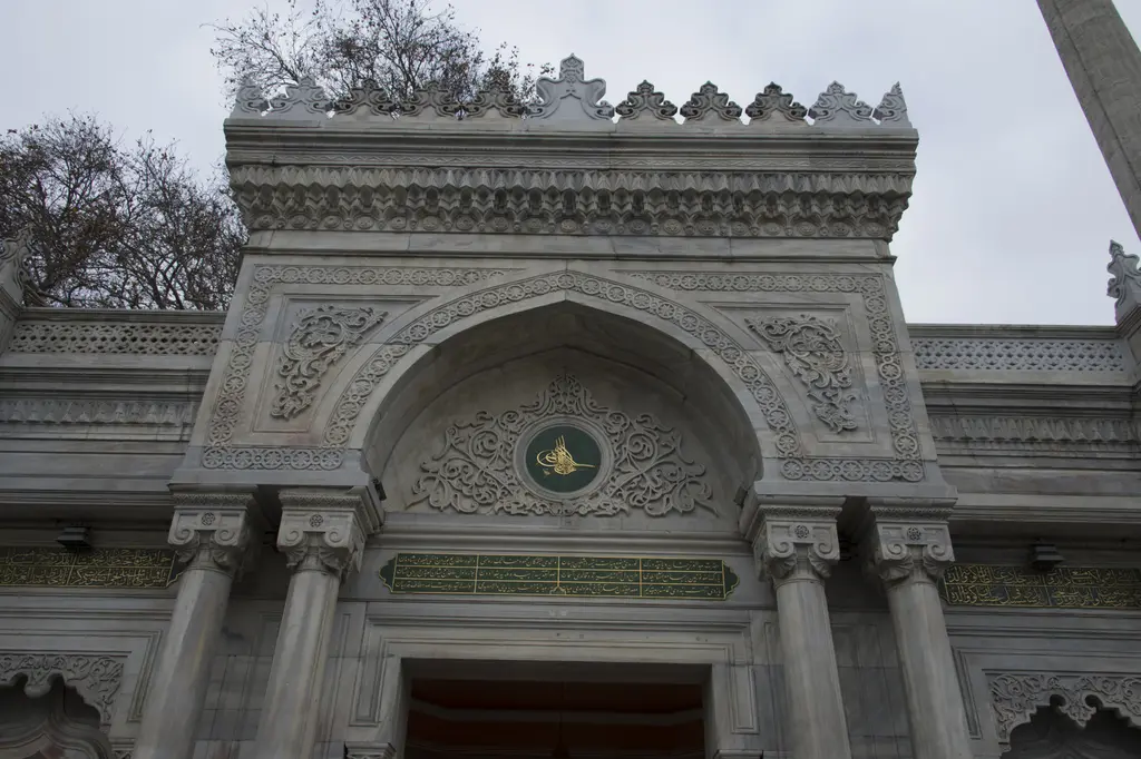 Pertevniyal Valide Sultan Camii'nin avlu kapısı yakından; sütunlar, kemer içinde tuğra, oyma bitki motifleri ve taş işçiliği.