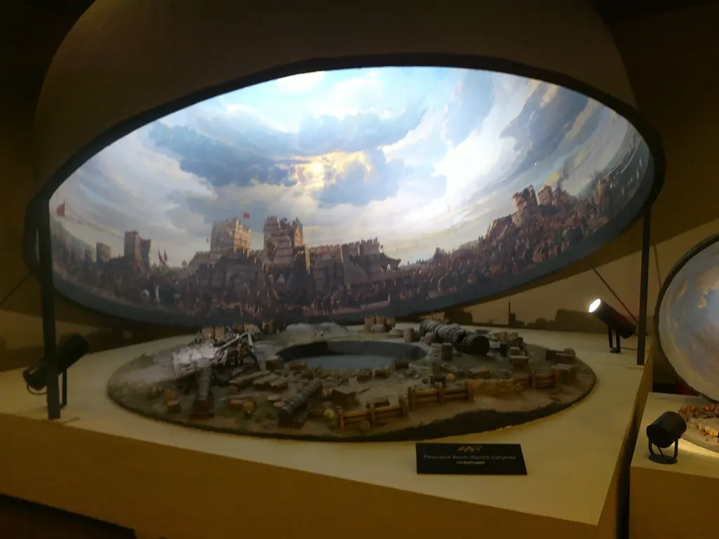 Panorama salonunun genel görünümü; yukarıda kavisli resim kuşağı, ortada aydınlatılmış maket ve yanında küresel bir sergi öğesi.