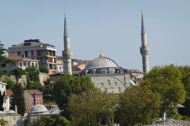 Üsküdar'da Mihrimah Sultan Camii; çift minareli kubbeli cami, önünde geniş son cemaat yeri, ağaçlar ve iskele meydanı.