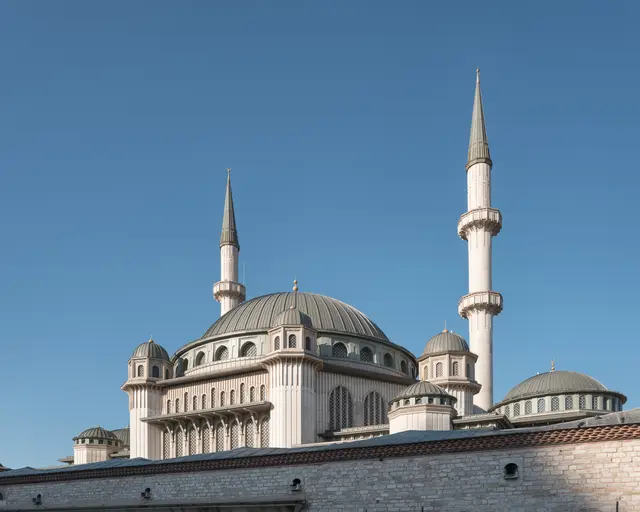 Taksim'de Taksim Camii; krem taş cephe, kurşun grisi merkezî kubbe, çevresindeki küçük kubbeler ve iki yanda ince, iki şerefeli minareler.