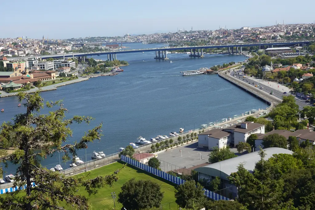 Pierre Loti Tepesi'nden Haliç; ormanlık yamaç, kıyıdaki semtler, Haliç'in kıvrılan suyu ve uzakta tarihi yarımadanın silueti.