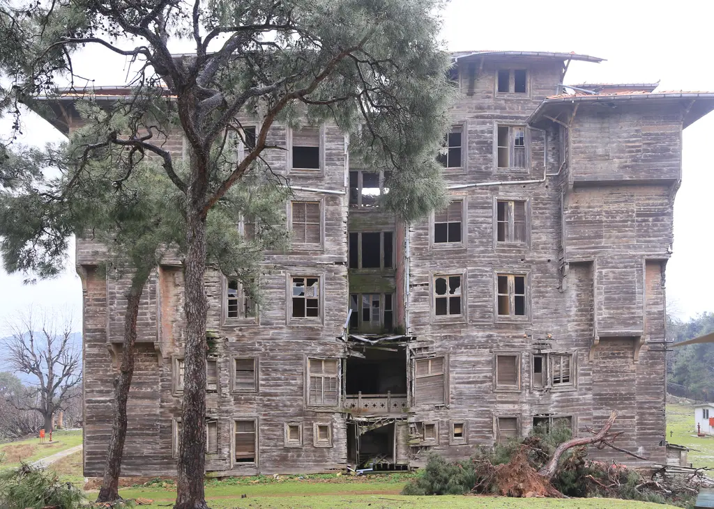 Büyükada Rum Yetimhanesi'nin ön cephesi; altı sıra pencereli gri ahşap kule kanadı ve önünde çam ağacı.