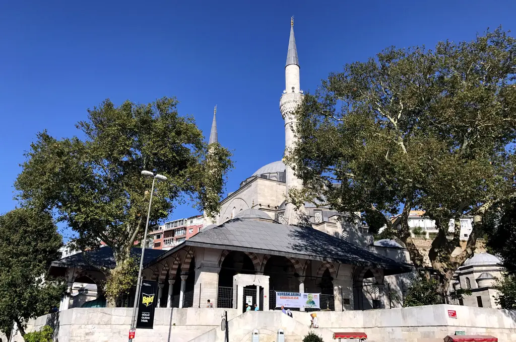 Mihrimah Sultan Camii; ağaçların arasından görünen kubbe, iki ince minare ve son cemaat yerinin çatısı.
