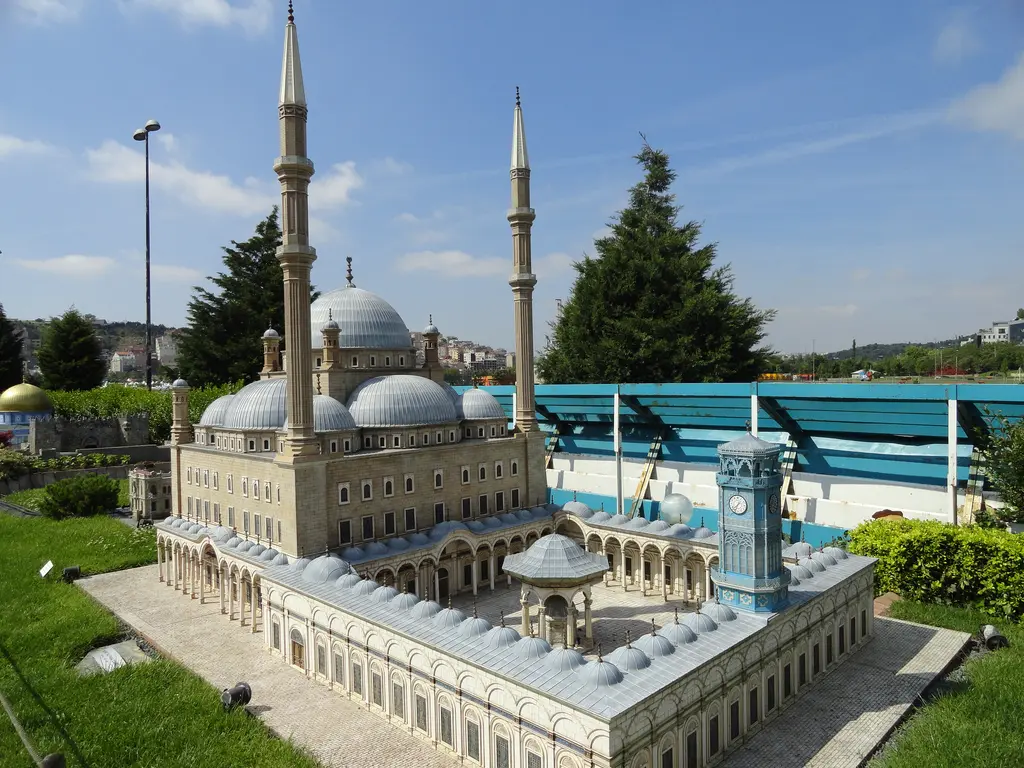 Miniatürk'te Kahire Mehmed Ali Paşa Camii maketi; gri beyaz merkezî kubbe, iki ince minare, avlu ve saat kulesi, arkada mavi duvar.
