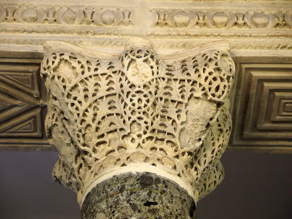 Küçük Ayasofya Camii'nde oyma mermer sütun başlığı; dantel gibi delik işlenmiş akantus yaprakları, üstünde panolu impost bloğu ve altta benekli koyu renkli sütun gövdesi.