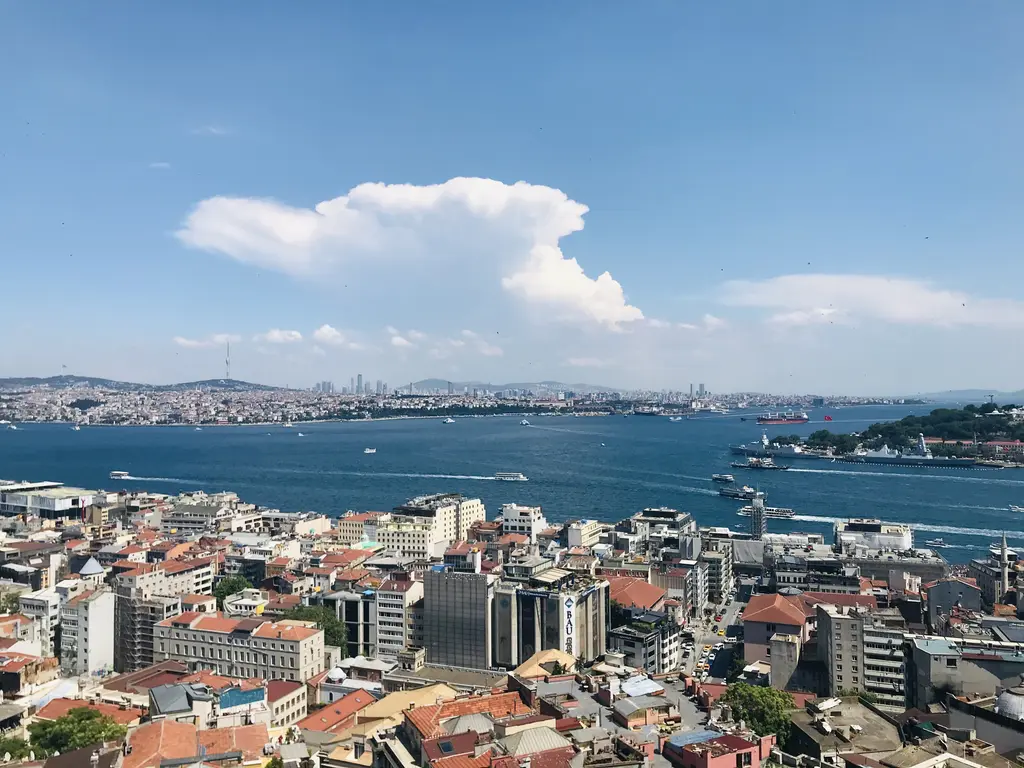 Galata Kulesi'nin terasından Boğaz; önde Karaköy'ün çatıları, ortada geniş su ve karşı kıyıda Anadolu yakası ve sağda ağaçlık Sarayburnu.