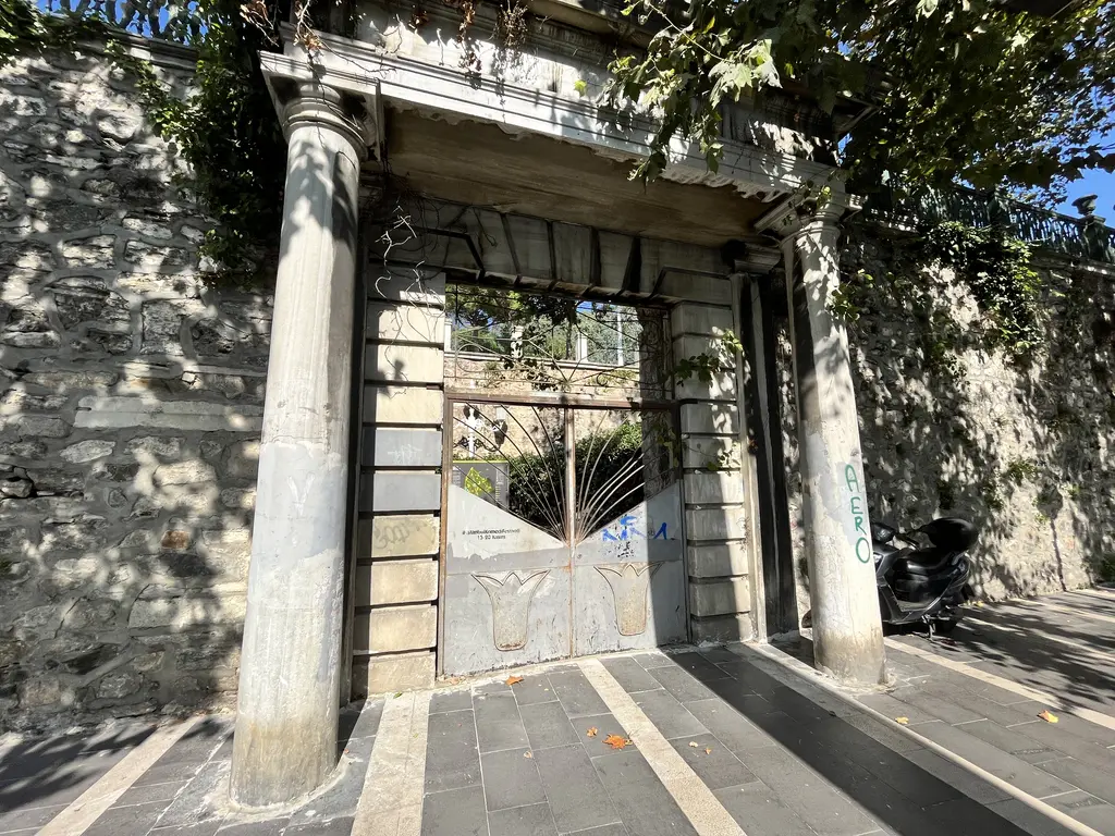 Yıldız Parkı'nda Çırağan Caddesi'ne açılan eski bir kapı; taş duvara oturan iki sütun, üstte alınlık, ortada demir kanat.