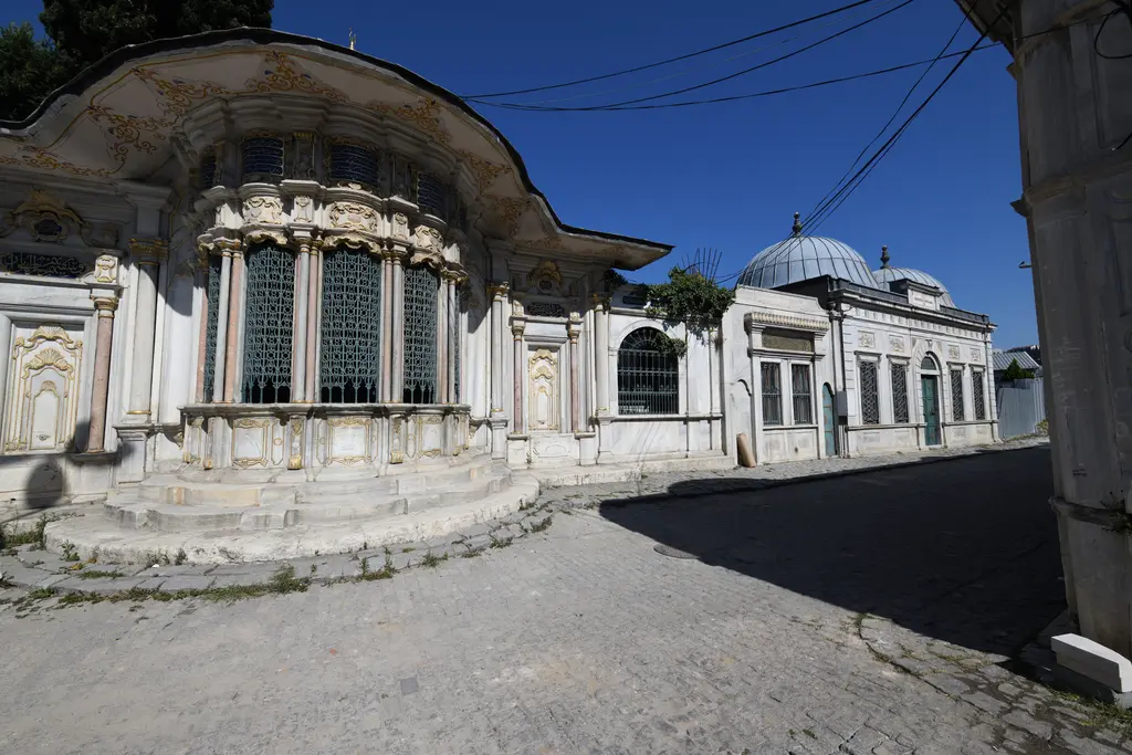 Mihrişah Valide Sultan Sebili; geniş dalgalı saçak, yaldızlı süslemeler, dökme demir şebekeli pencereler ve önündeki mermer basamaklar.