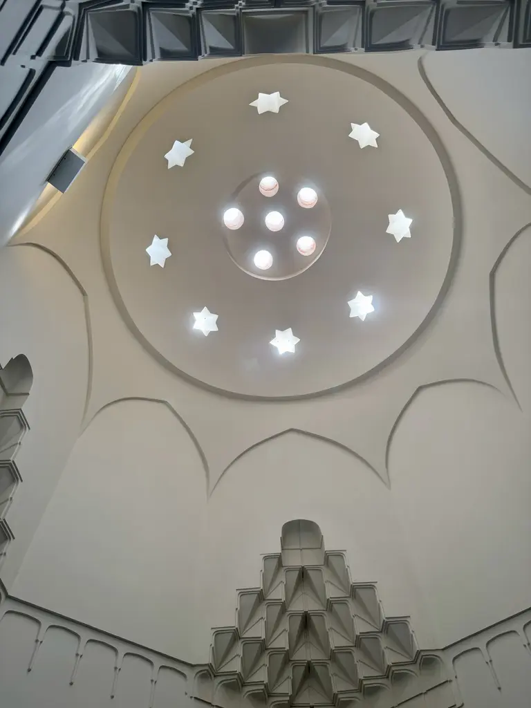 Çinili Hamam'da bir kubbenin içi; yıldız biçimli fil gözleri, ortada camlı yuvarlak aydınlık, mukarnaslı geçiş ve açık gri sıva.