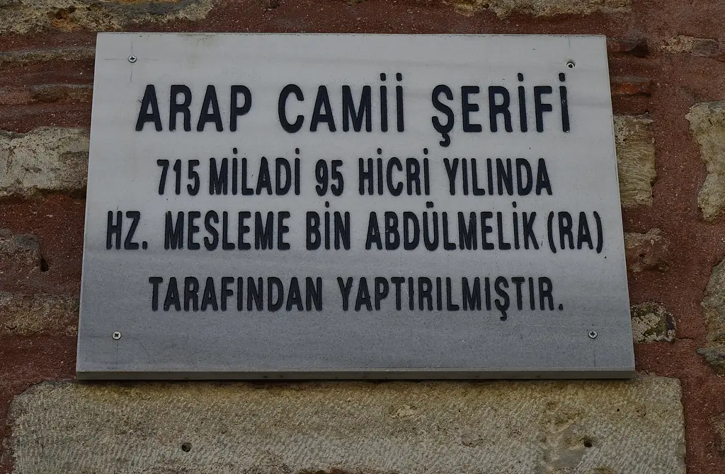Arap Camii'nin duvarında mermer levha; siyah harflerle caminin 715'te Mesleme bin Abdülmelik tarafından yaptırıldığını yazan metin.