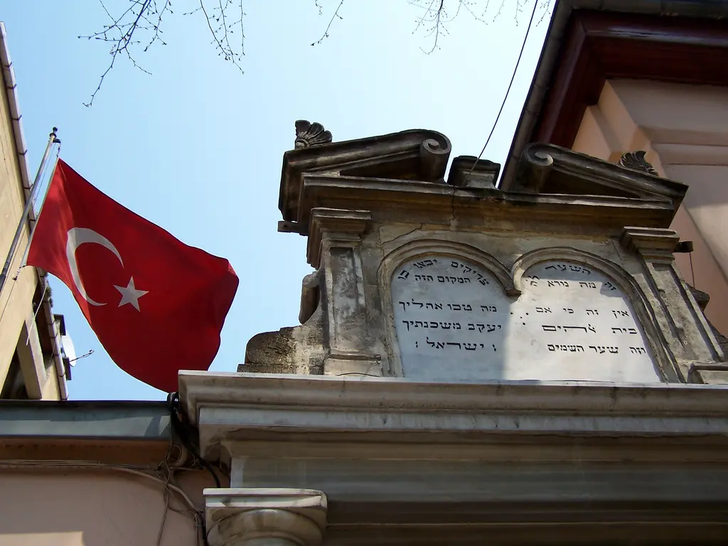 Kuzguncuk'ta Bet Yaakov Sinagogu'nun girişi; İbranice yazılı mermer kitabe, kıvrımlı alınlık ve yanında Türk bayrağı.