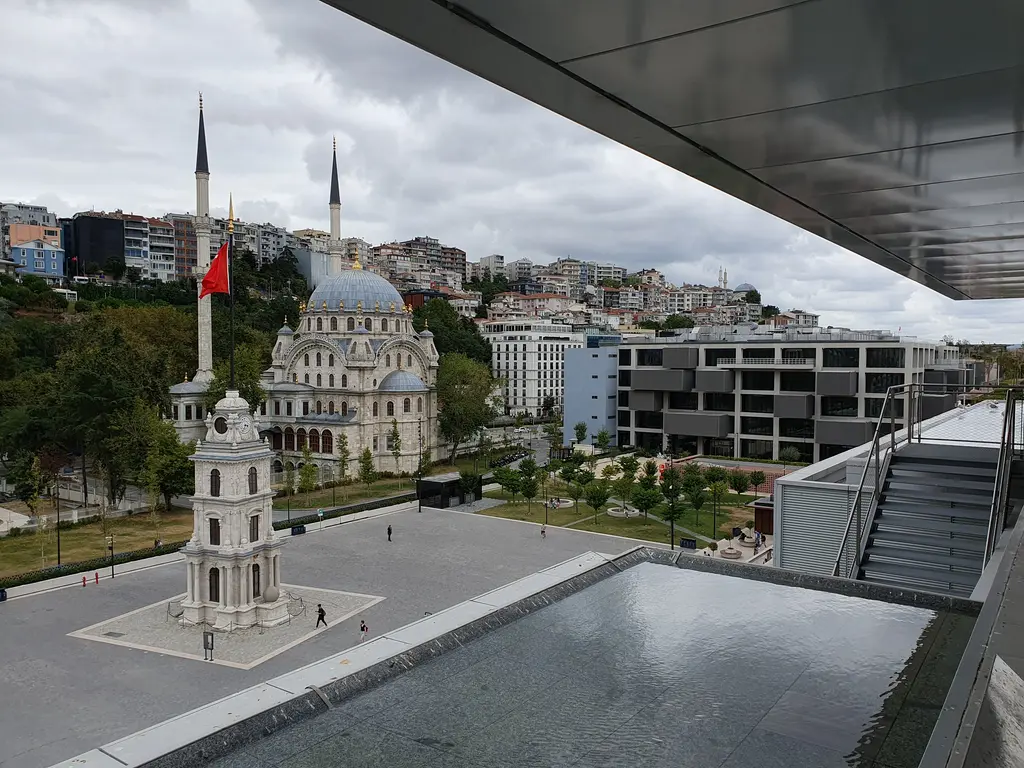 İstanbul Modern'in üst katından Tophane'ye bakış; önde sığ su havuzu, aşağıda Tophane Saat Kulesi ve Nusretiye Camii.