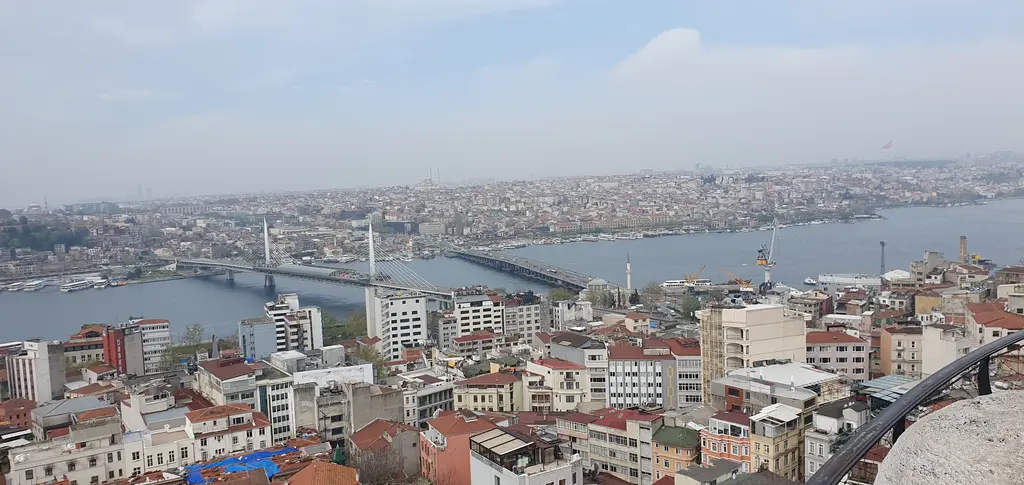 Galata Kulesi'nin terasından Haliç; suyun üzerinde Haliç Metro Köprüsü ile Atatürk Köprüsü, iki kıyıda yoğun yapılaşma.