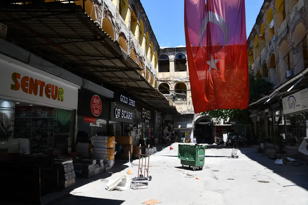 Büyük Yeni Han'ın avlusu; ortaya asılmış büyük Türk bayrağı, iki yanda toptancı dükkânları ve üst katların kemer dizileri.