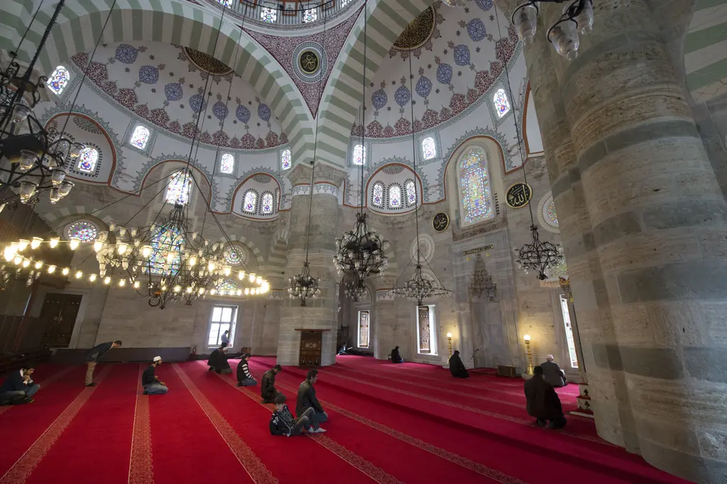 Mihrimah Sultan Camii'nin içi; kırmızı halılar, yuvarlak avizeler, kalın paye ve kemerlerin altında geniş harim.