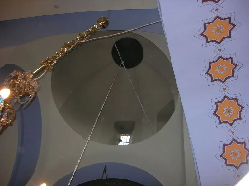 Kanlı Kilise'nin kubbesi içten; açık renkli boyalı kubbe, tepede küçük açıklık, sarkan avize zinciri ve yanda yıldız desenli kemer.