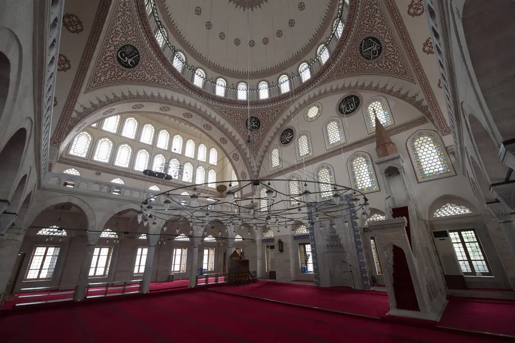 Zal Mahmud Paşa Camii'nin içi; kubbe kemerleri altında taş minber, çinili mihrap duvarı, sıra sıra pencereler ve kırmızı halı.