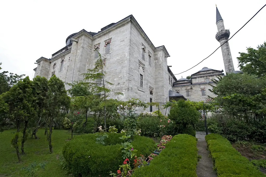 Caminin kıble tarafı bahçeden; almaşık taş duvar, iki sıra kemerli pencere, sağda sekizgen kubbeli türbe ve arkada tek minare.