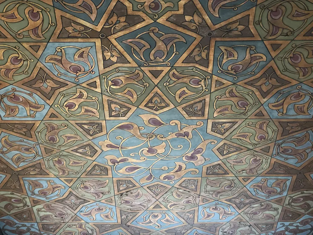 Şişli Camii'nde tavan bezemesi; mavi, kahverengi ve mor tonlarda yıldız geometrisi, kıvrık yapraklar ve altın hatlar.