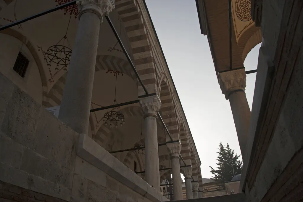 Zal Mahmud Paşa Camii'nin revağı; alttan bakışla mermer sütunlar, taş ve tuğla sıralı kemerler, asılı kandil ve gökyüzü.