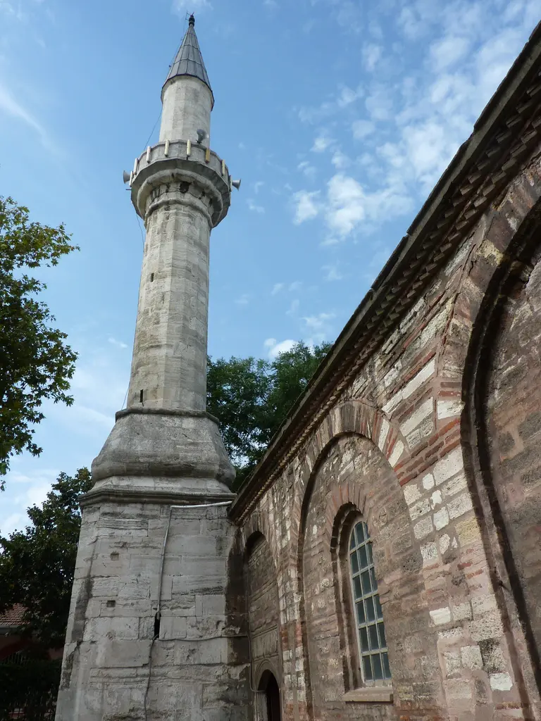 Fethiye Camii'nin minaresi alttan; beyaz badanalı gövde, şerefe korkuluğu, kurşun külah ve arkasında açık mavi gökyüzü.