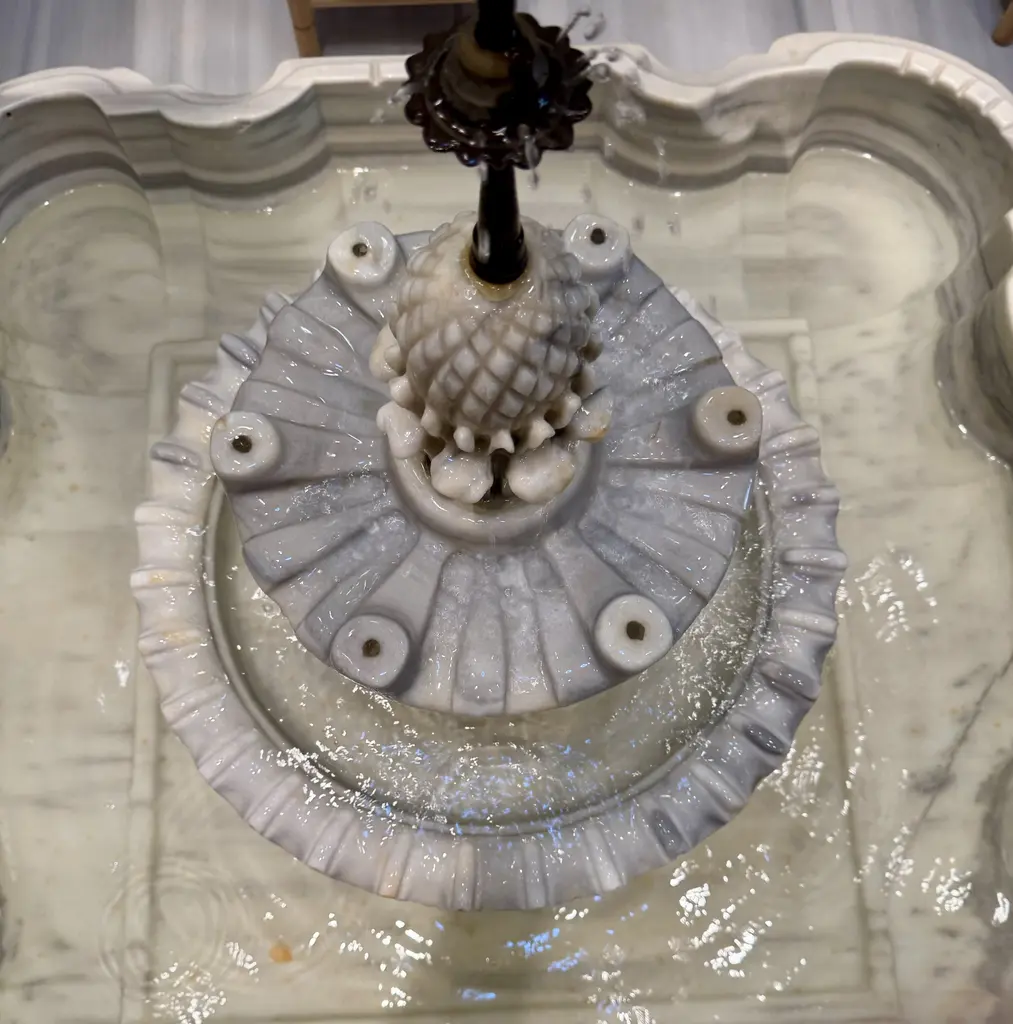 Çinili Hamam'da mermer havuzun fıskıyesi yakından; dilimli havuz teknesi, kozalak biçimli fıskıye başlığı ve çevreye yayılan su.