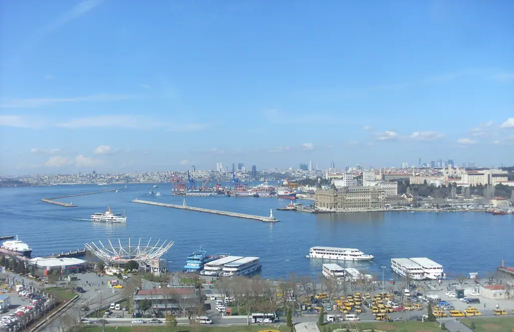 Kadıköy'de iskele ve Haydarpaşa Koyu; kıyıya yanaşmış vapurlar, mendirekler, kuleli gar binası ve uzakta Avrupa yakası.