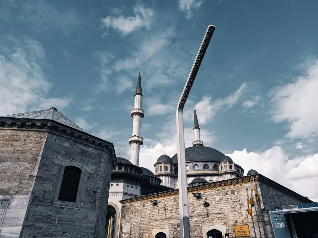 Taksim'de Taksim Maksemi ve arkasında Taksim Camii; önde kesme taş yapı, arkada kubbeler ve iki ince minare.