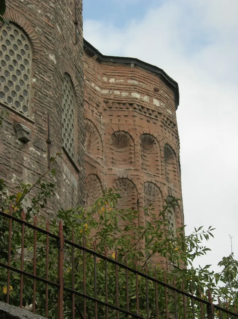 Gül Camii'nin yan apsisi yakından; zikzak tuğla silmenin altında sıra sıra kemerli kör nişler, solda gövdenin petek gözlü pencereleri.