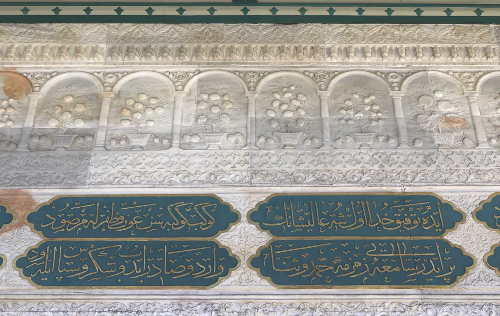 Tophane Çeşmesi'nden ayrıntı; üstte kemerli küçük nişlerde saksılı meyve ağacı kabartmaları, altta yeşil zeminli altın yazılı kitabe kartuşları.