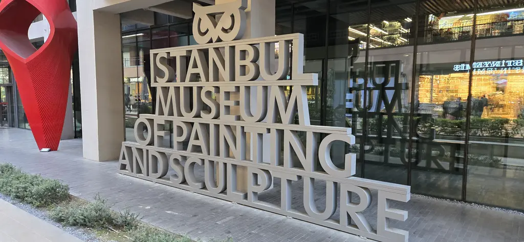 İstanbul Resim ve Heykel Müzesi'nin girişinde büyük gri harflerle müzenin İngilizce adı ve solda kırmızı bir heykel.