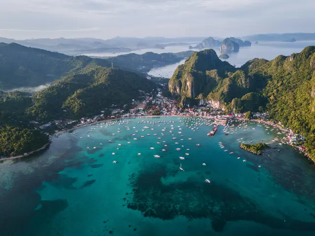 Tayland'da Phi Phi Adaları; yeşil tepelerle çevrili turkuaz koy, kıyıdaki yerleşim ve suda demirli yüzlerce tekne.