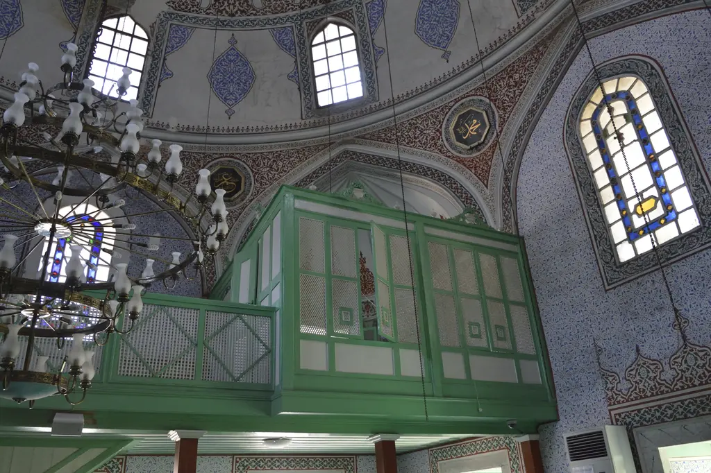 Haseki Sultan Camii'nde yeşil boyalı ahşap hünkâr mahfili; kafesli korkuluklar, avize, renkli camlı pencereler ve kalem işi duvarlar.