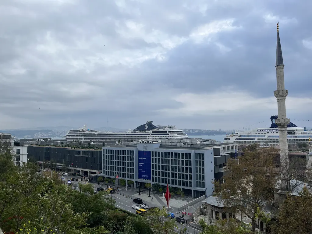 Tepeden Galataport; arkada yanaşmış iki büyük kruvaziyer gemisi, önde ofis blokları, sağda tek şerefeli bir minare.