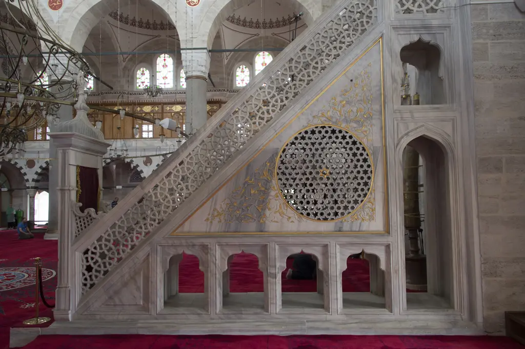 Mihrimah Sultan Camii'nin minberi; beyaz mermer gövde, şebekeli korkuluk, yan yüzdeki yuvarlak geçme rozet ve tepesinde külahlı köşk.