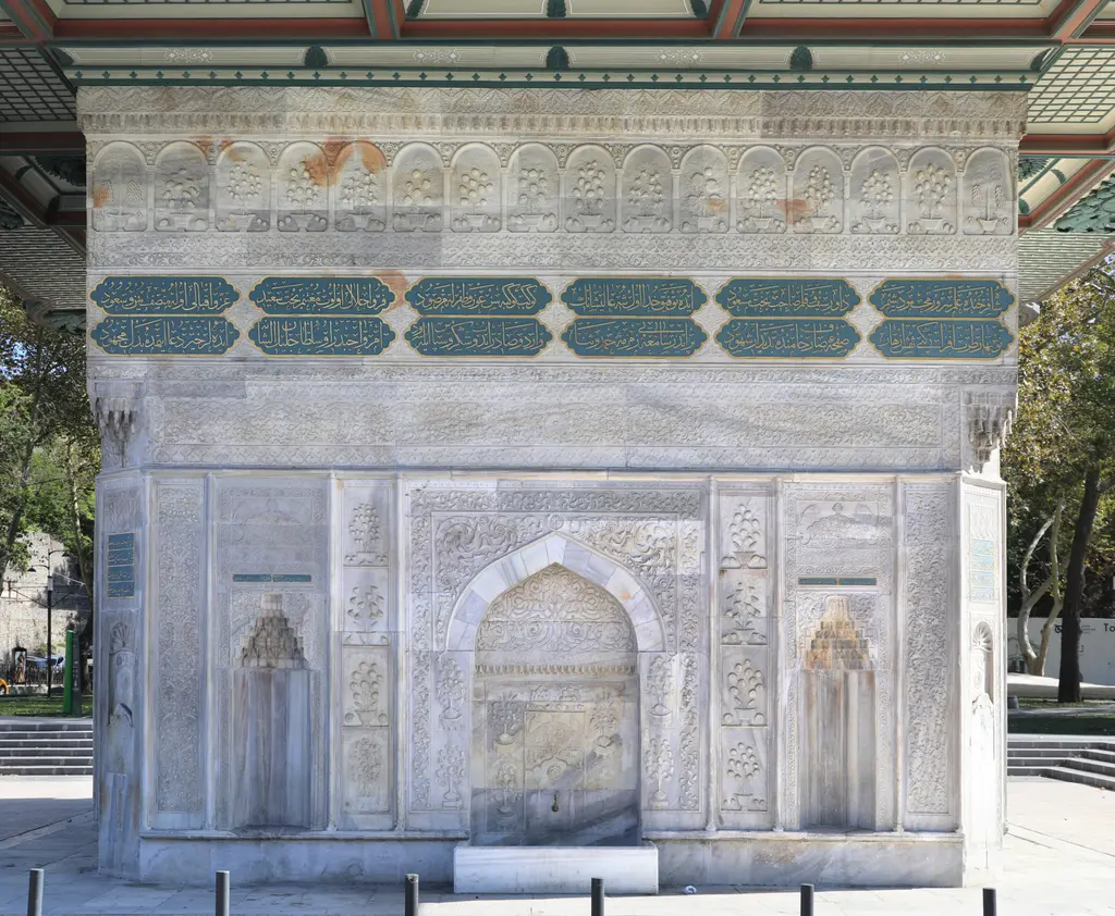 Tophane Çeşmesi'nin bir cephesi; ortada sivri kemerli büyük niş, yanlarda küçük nişler, yüzeyde ince kabartmalar ve yeşil yazı kuşağı.