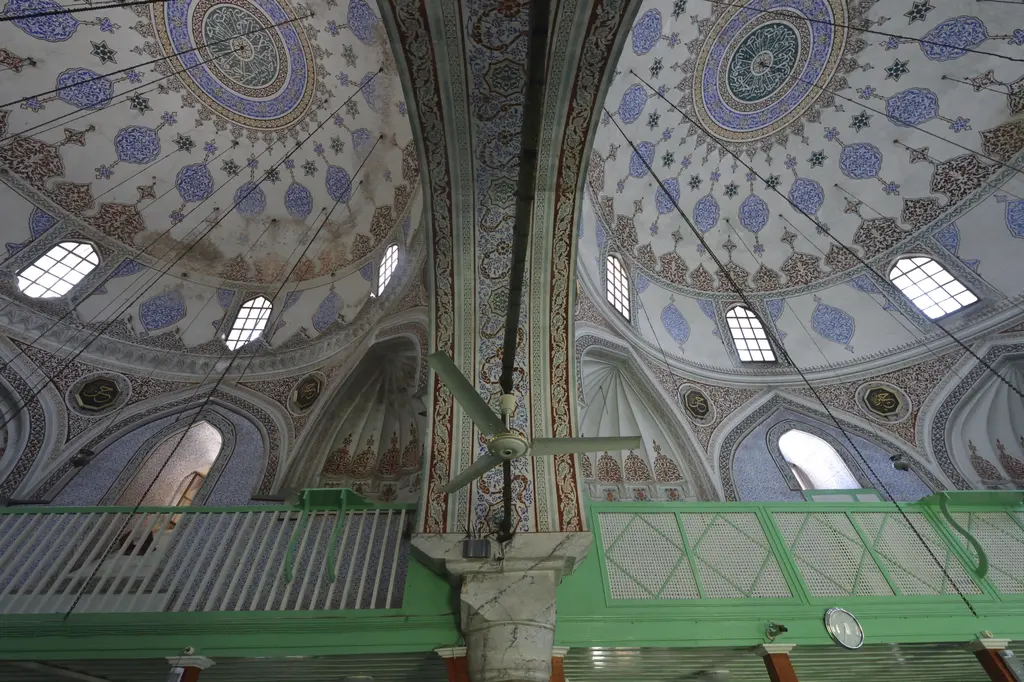 Haseki Sultan Camii'nde iki kubbenin birleştiği yer; kalem işi desenli kubbeler, ortada kemer ve altta yeşil korkuluklu ahşap mahfil.