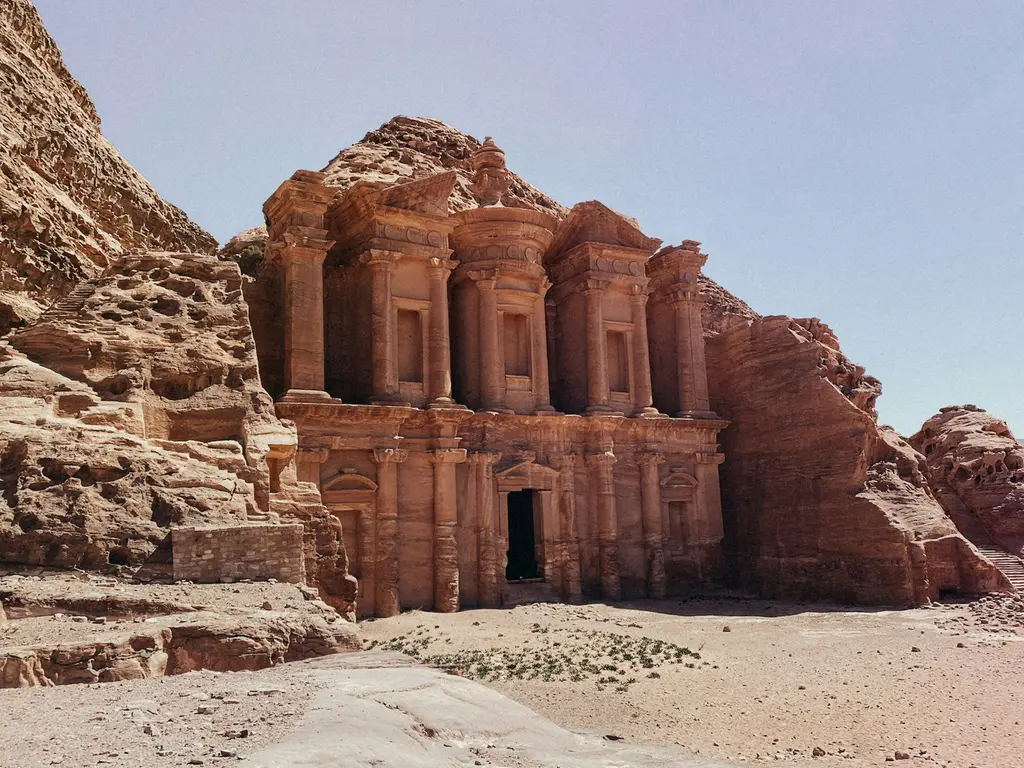 Petra'da kayaya oyulmuş devasa cephe; iki katlı sütunlu düzen, ortadaki yuvarlak külahlı bölüm ve önündeki geniş taşlık düzlük.