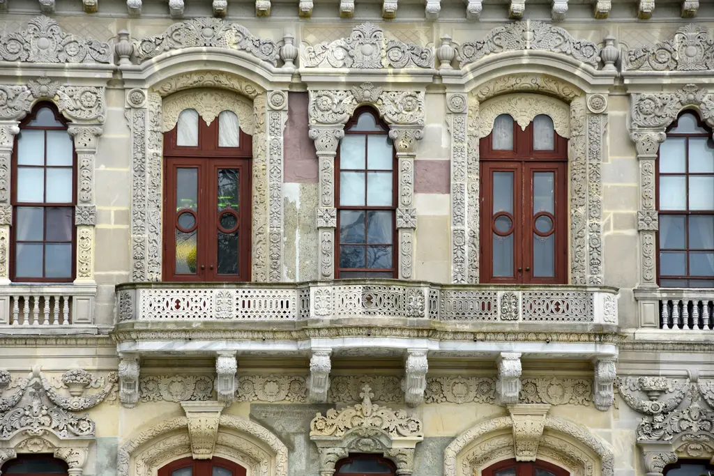 Küçüksu Kasrı'nın deniz cephesinde pencereler; kırmızı çerçeveli kemerli pencereler, mermer balkon korkuluğu ve çevrelerinde yoğun kabartmalar.