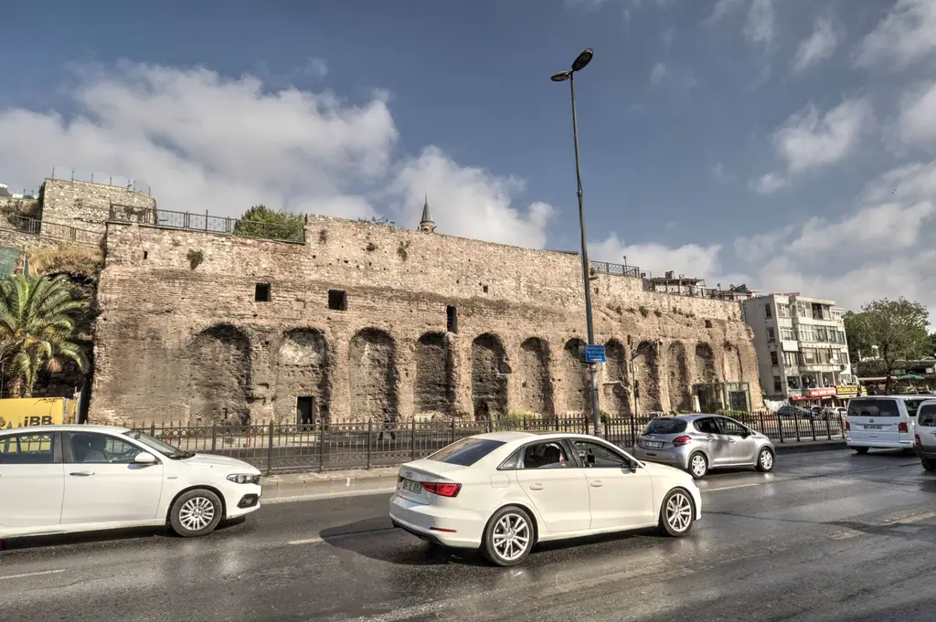 Atatürk Bulvarı'ndan Zeyrek Sarnıcı; yol boyunca uzanan kemerli nişli taş ve tuğla cephe, önde beyaz arabalar, sokak lambası ve bulutlu gök.