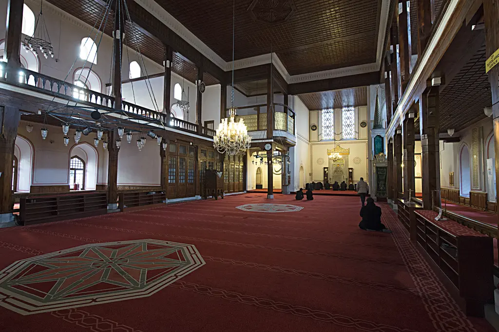 Arap Camii'nin içi; koyu renkli düz ahşap tavan, sıra sıra pencereler, avize çemberleri ve iki yanda ahşap mahfiller.