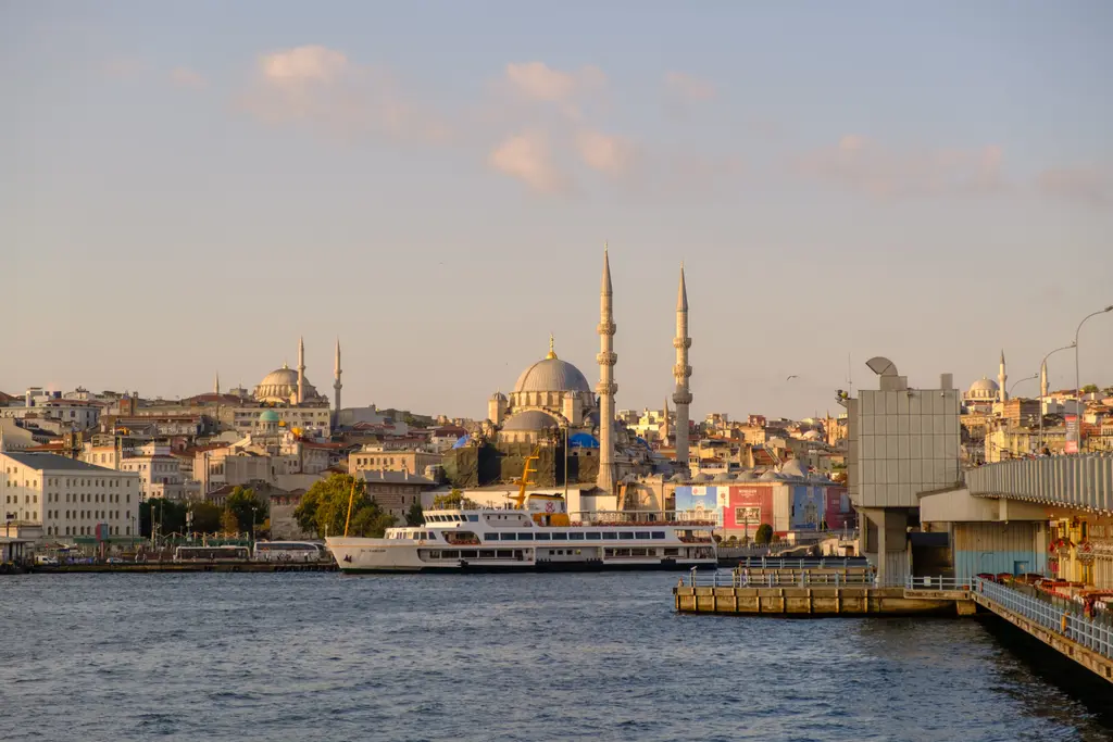 Galata Köprüsü'nden Eminönü kıyısı; Yeni Cami, tepede Süleymaniye, kıyıda iskele ve vapurlar, akşam ışığı.