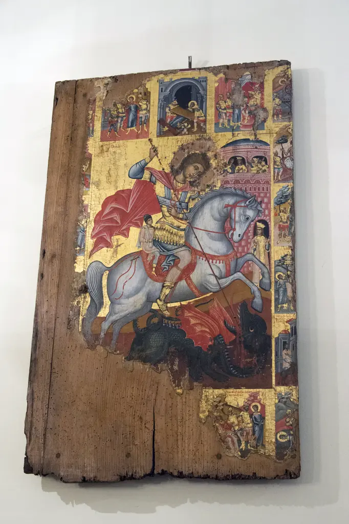 Panayia Balino Kilisesi'nde ahşap ikona; beyaz atlı, mızrağıyla ejderhayı öldüren aziz, çatlamış ahşap pano ve kenarında küçük sahneler.
